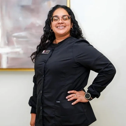 Ednaliz, a dental team member, smiles while wearing her black dental scrubs at the practice.