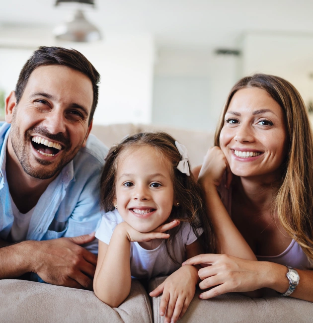 Happy family smiling together on couch in dental office waiting room.