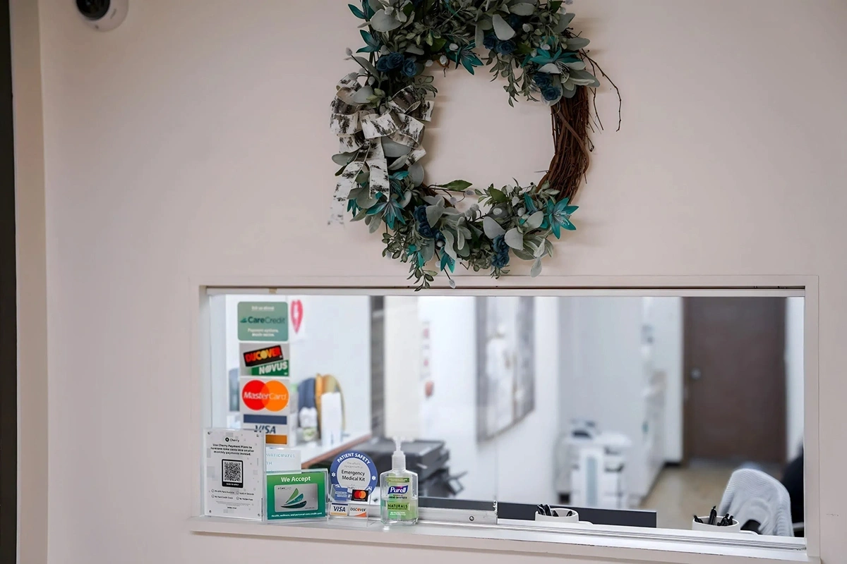 Dental office check-in window displaying payment methods and hand sanitizer at Fitchburg practice.