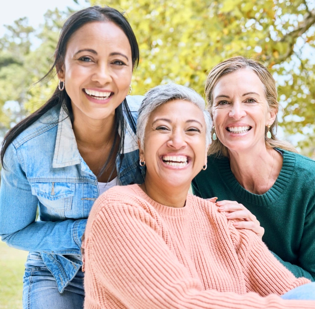 Three smiling women representing preventative dental care and oral health in Fitchburg, MA.