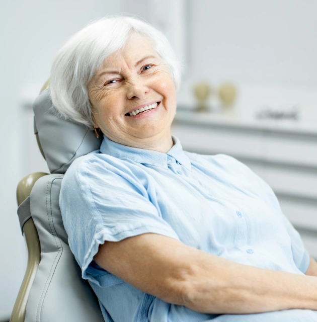 Smiling senior woman patient relaxed in dental chair after root canal therapy treatment.