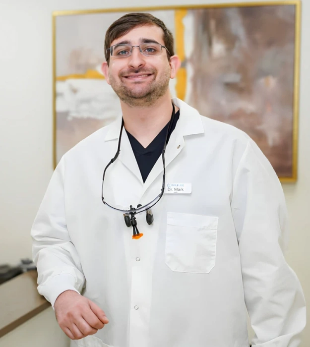 Dr. Mark Berenshteyn, dentist, smiling in white coat with stethoscope at Fitchburg dental practice.